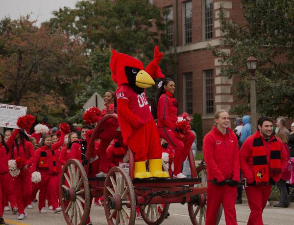 Reggie the Redbird stands on a chariot among cheerleaders during the Homecoming Parade.